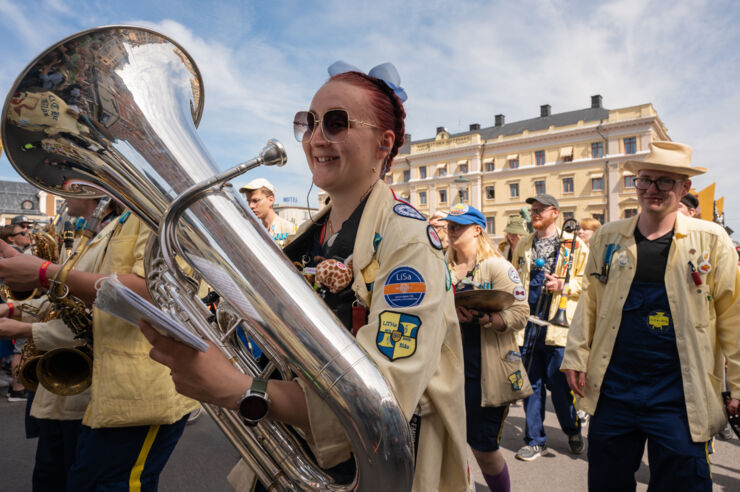 Orchestra wearing yellow jackets walk along a street