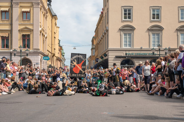 An orchestra lies on the street, surrounded by people