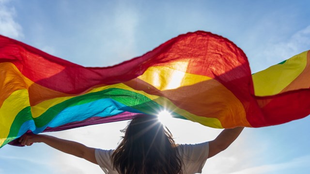 A woman waving a Pride flag. 