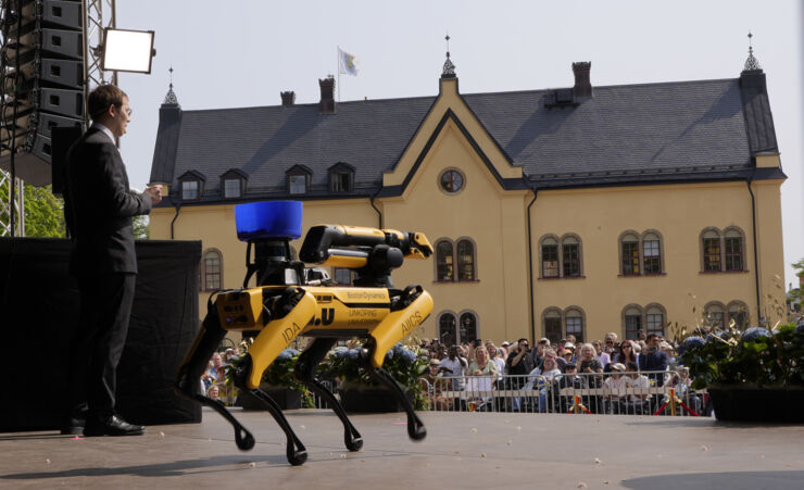 Man på scenen med roboten Spot och publik framför.