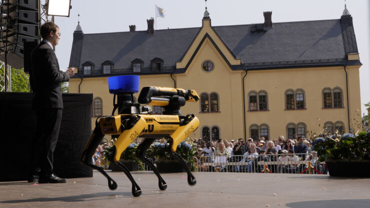 Man på scenen med roboten Spot och publik framför.