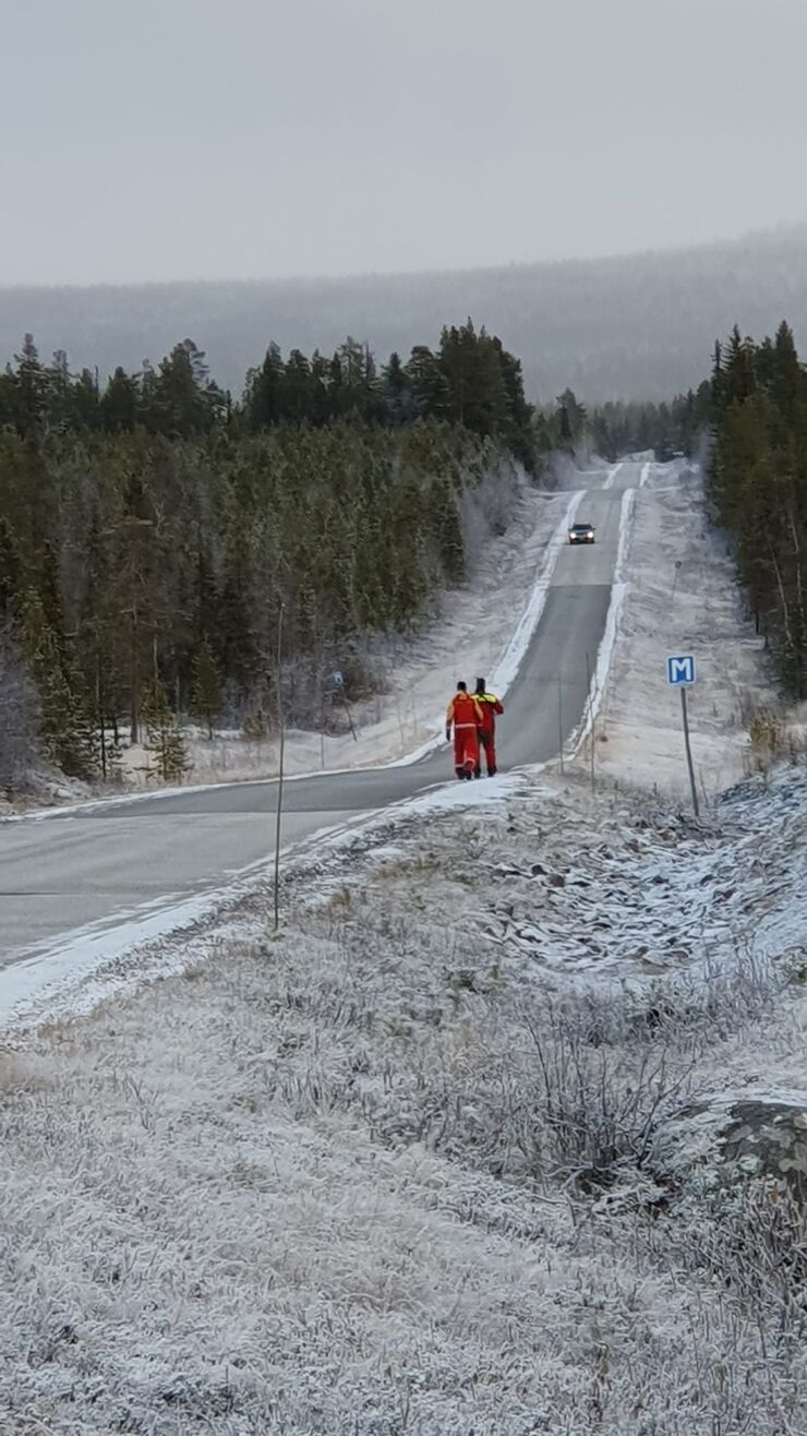 Två personer som går längs en väg för att söka nödställda.