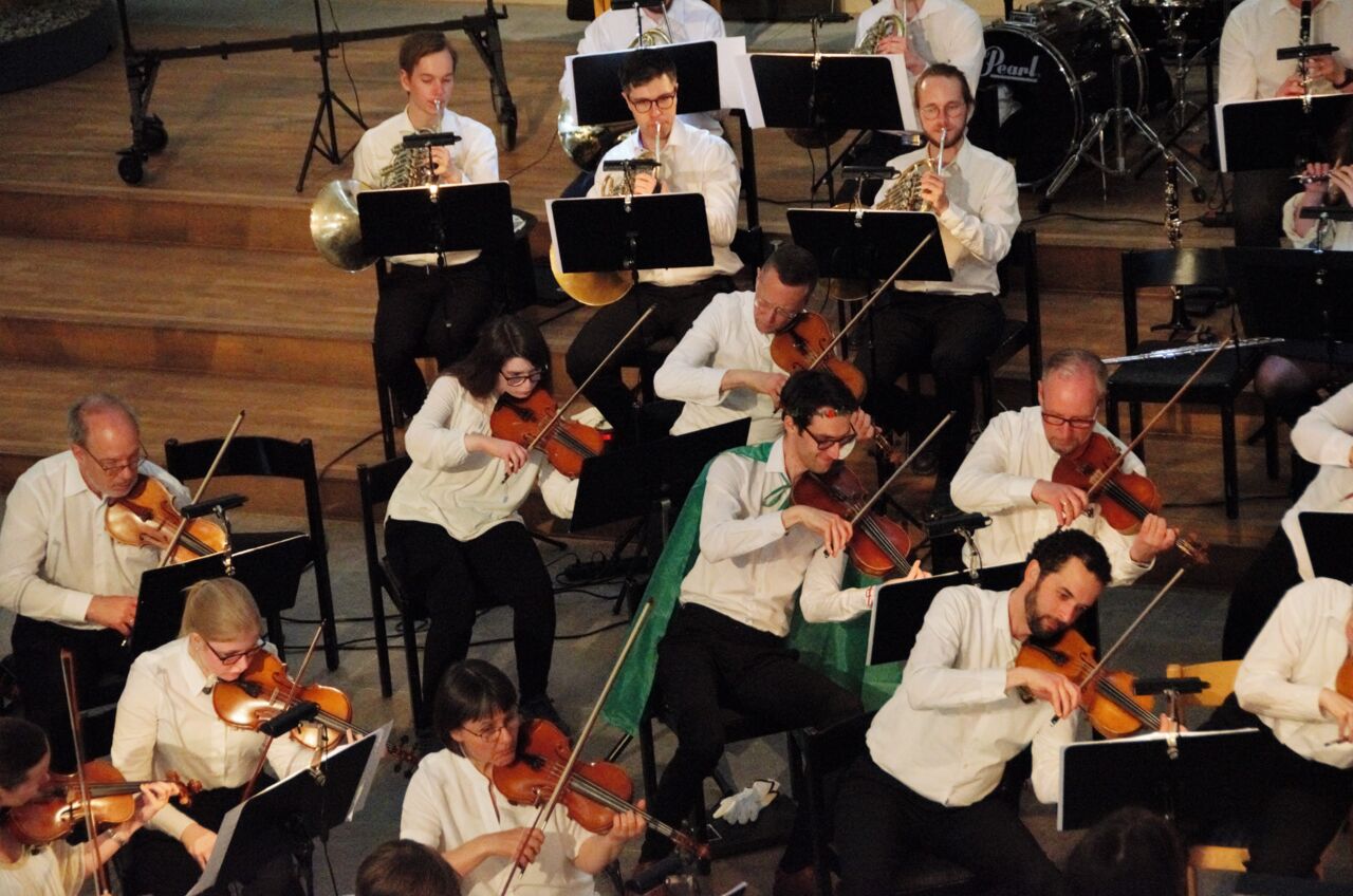 Orkestern är klädd i cape och lutar sig när de spelar