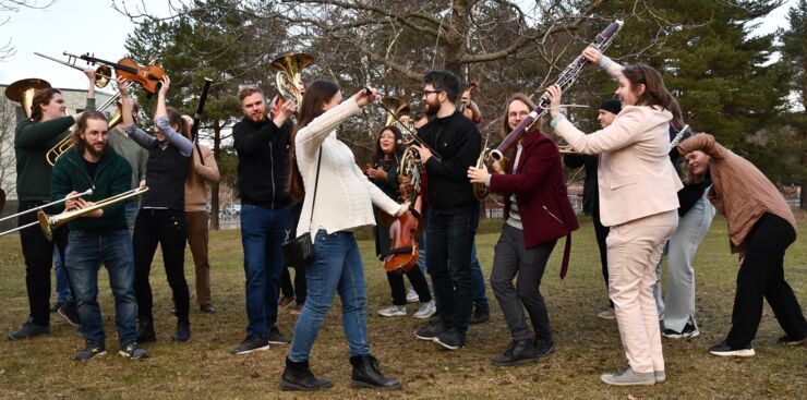 The orchestra standing outside holding their instruments over the head.