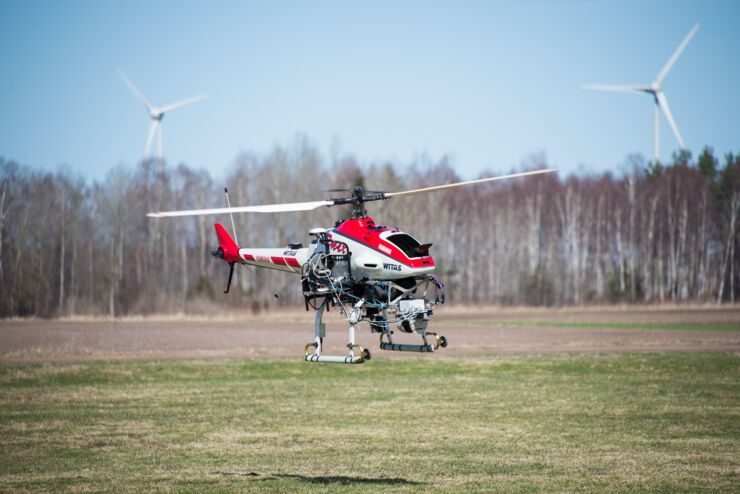 Rmax helicopter flying over a field of grass.