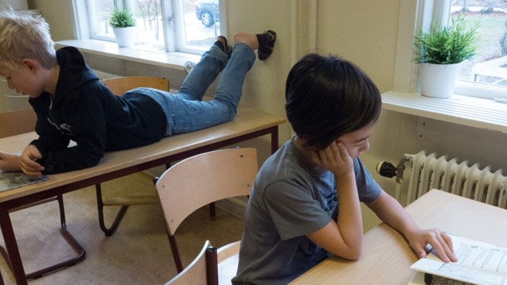 Två pojkar i ett klassrum som läser böcker. 