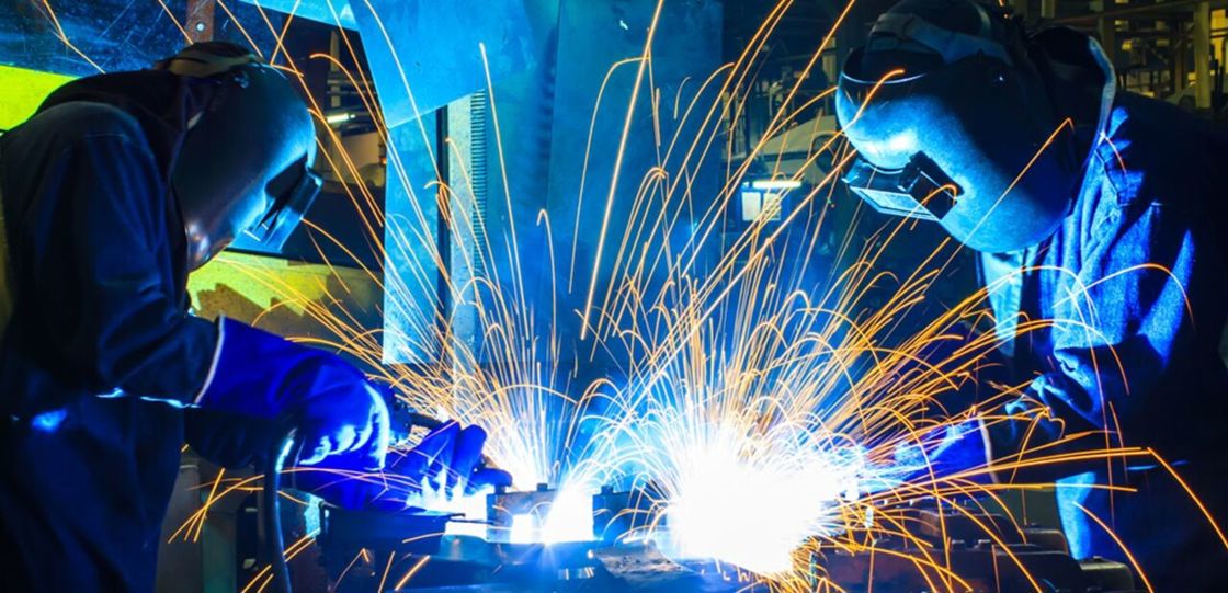 Two people in protecting clothes welding.