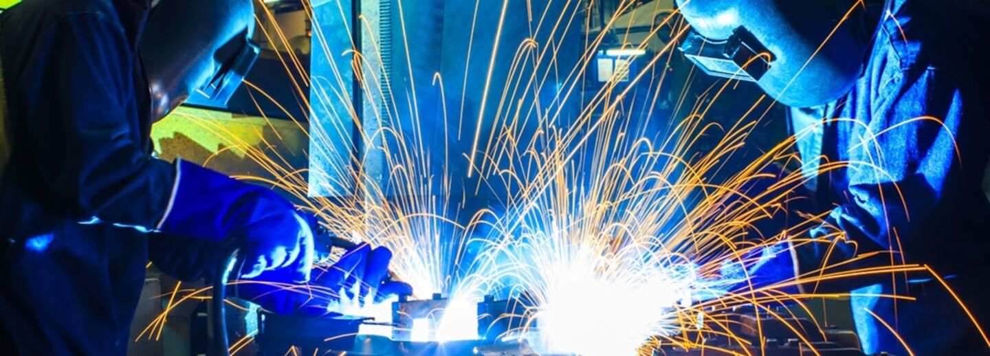 Two people in protecting clothes welding.