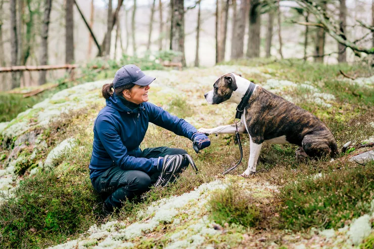 En kvinna med hund i skogen.
