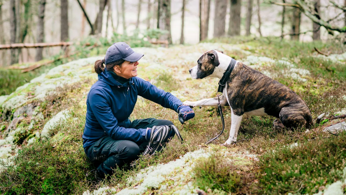 En kvinna med hund i skogen.