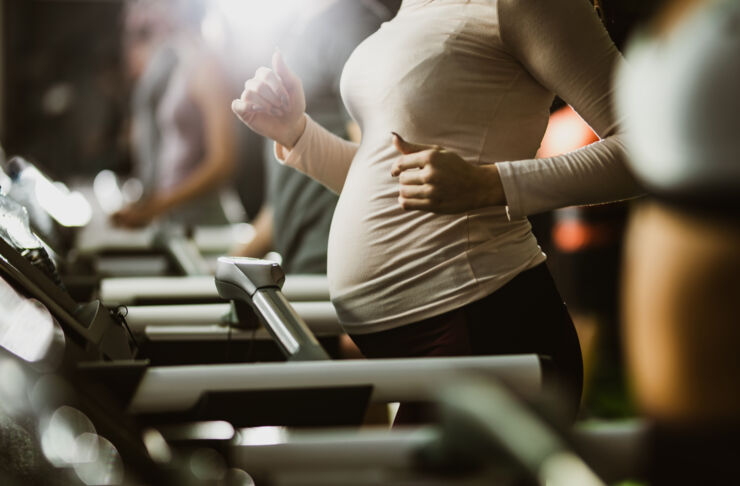 gravid kvinna joggar på löpband.