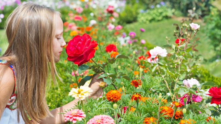 Flicka luktar på blomma.