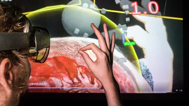 Hand infront of screen with digital autopsy.