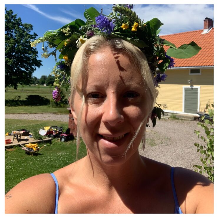 Episodeguest Therese Lindkvist is standing outside with flowers in her hair.