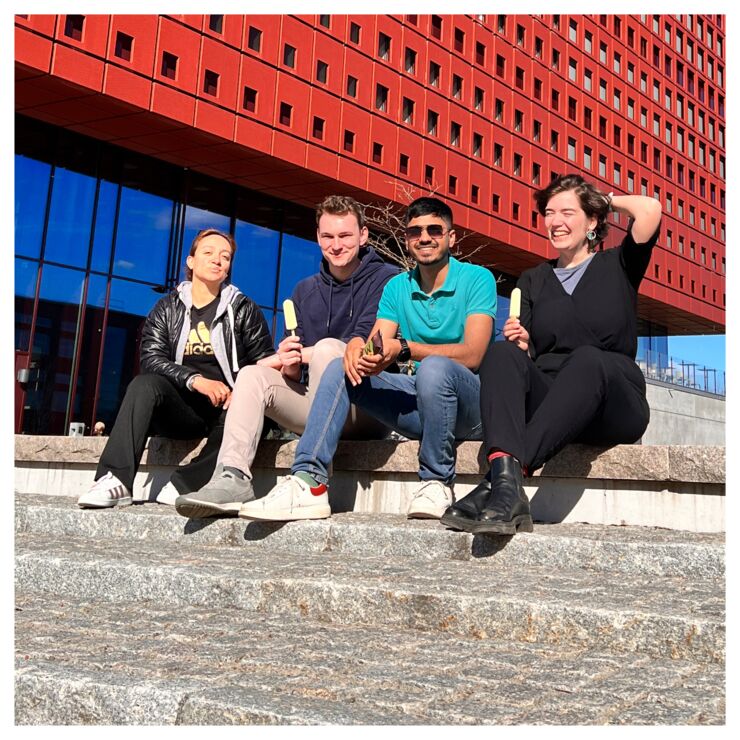 A group of people sitting outside in the sun outside Studenthuset at Campus Valla.