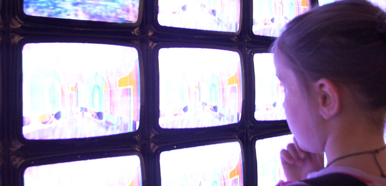 A boy watching television screens.