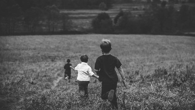 Barn springer på ett fält