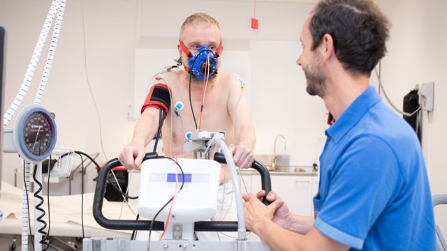 Man på motionscykel med andningsmask övervakas av manlig läkare.
