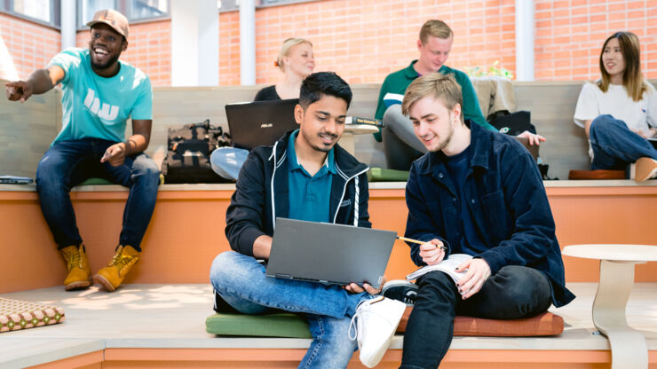 Grupp studenter där två sitter vid en bärbar dator