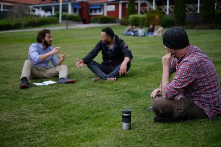 Group leaders from WCCM discuss on the grass at Sandvik Gård.