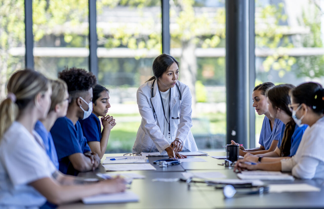 a group of medical students sit around a table and discuss. 