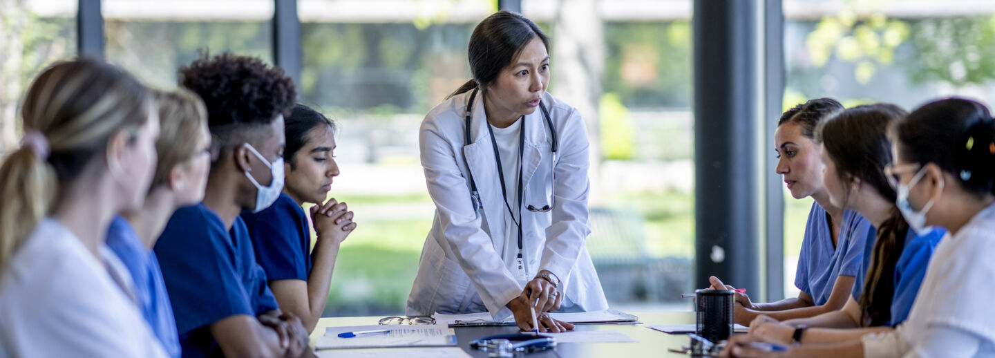 a group of medical students sit around a table and discuss. 