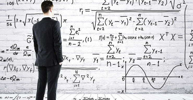 a man in a suit looks at a board with different formulas.