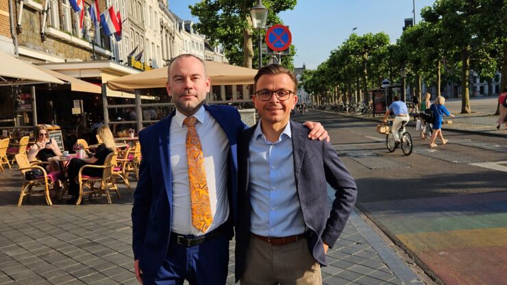 Two men standing ans smiling towards camer on the  street in France.