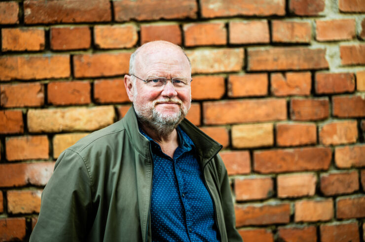 Portrait of Ola Larsmo next to a wall.