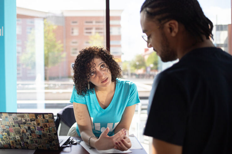 A woman wearing a LiU-T-shirt gives information to a student. 