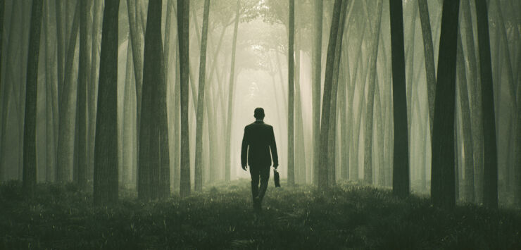 a man in a suit walks in the forest.