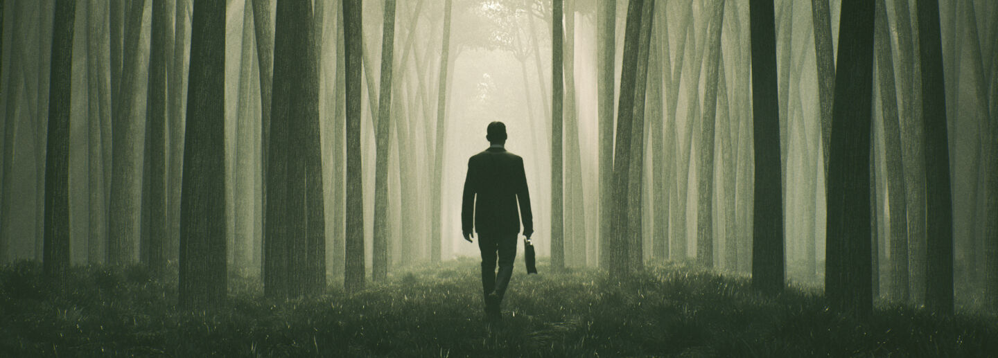 a man in a suit walks in the forest.