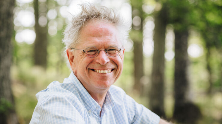 Portrait picture of Björn-Ola Linnér sitting outside with some trees in the background.