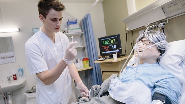 En sjuksköterskestudent tränar på att ta ett prov på en patientdocka.