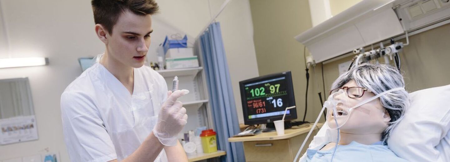 En sjuksköterskestudent tränar på att ta ett prov på en patientdocka.