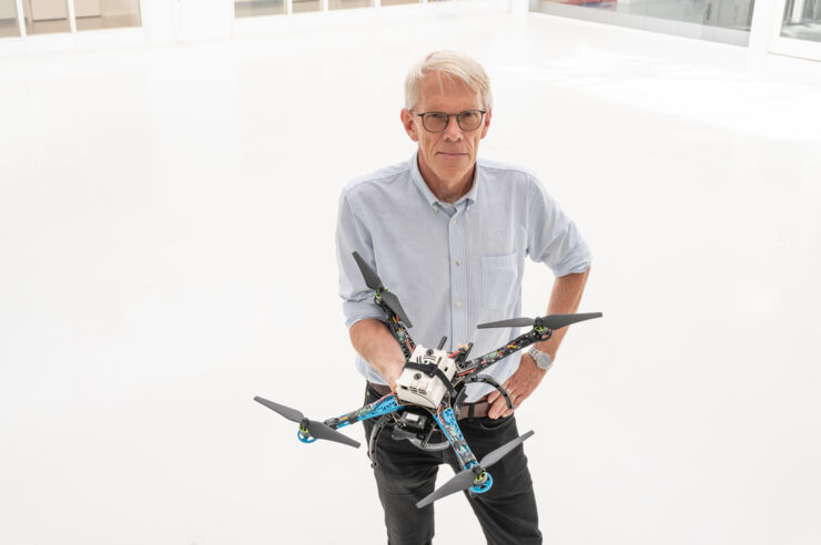 Svante Gunnarsson standing in a white room holding an unmanned aerial vehicle (UAV). 