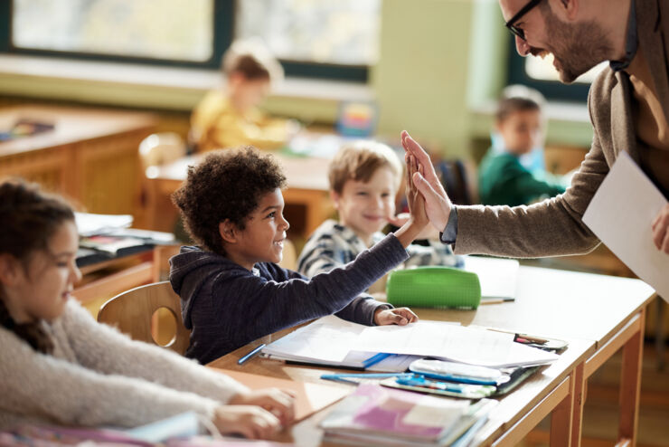 Lärare och elev gör en high-five i klassrum.