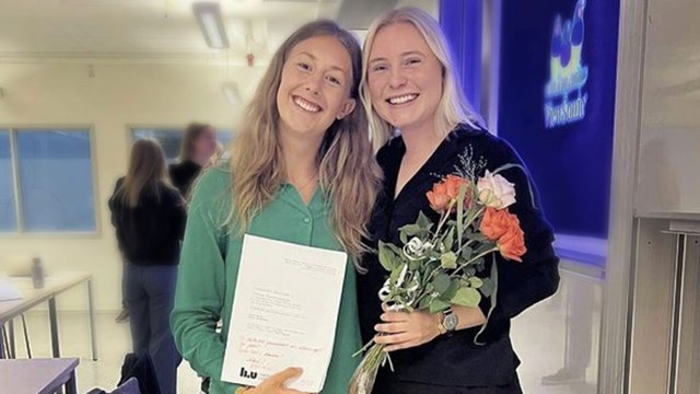 Two women with diploma and flowers.