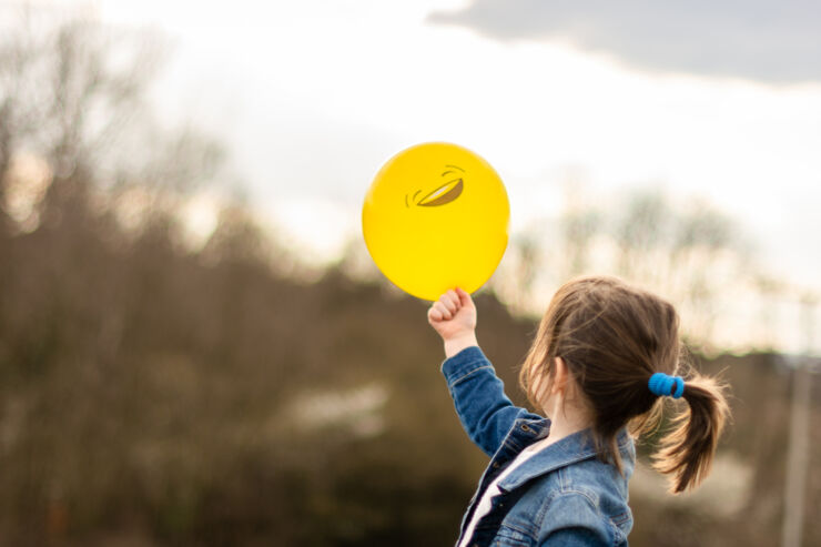 Child holding yellow ballon with a smile