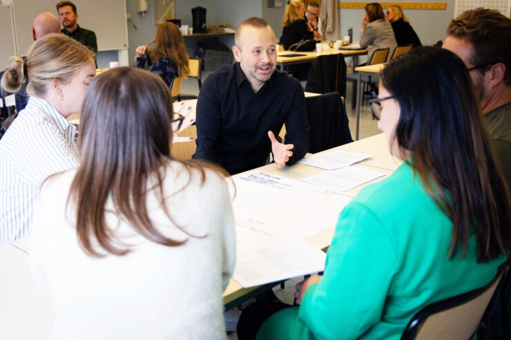 Forskare diskuterar med yrkesverksamma i en klassrumsmiljö.