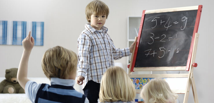 A boy standing next to a black board. 