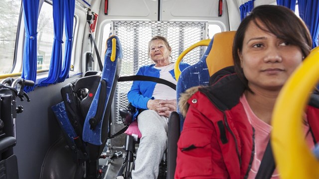 An elderly woman travelling by public transport.