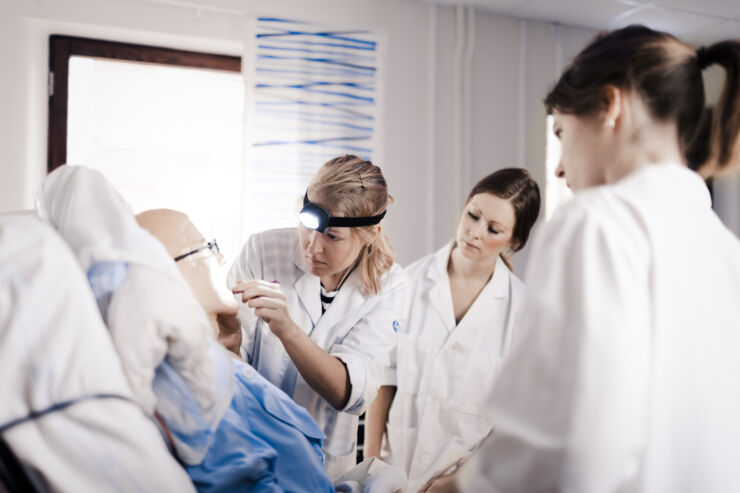 Läkarstudenter tränar undersökning på en simulatordocka 