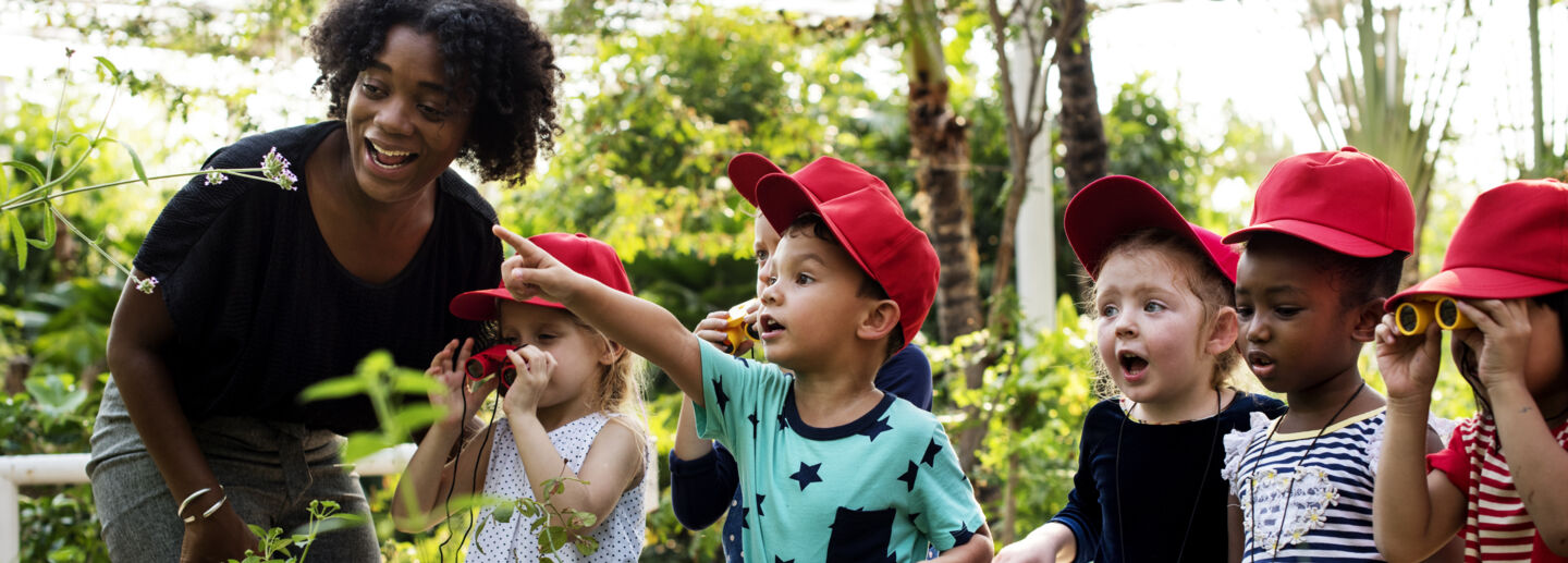 A group of children looking at nature with their teacher.