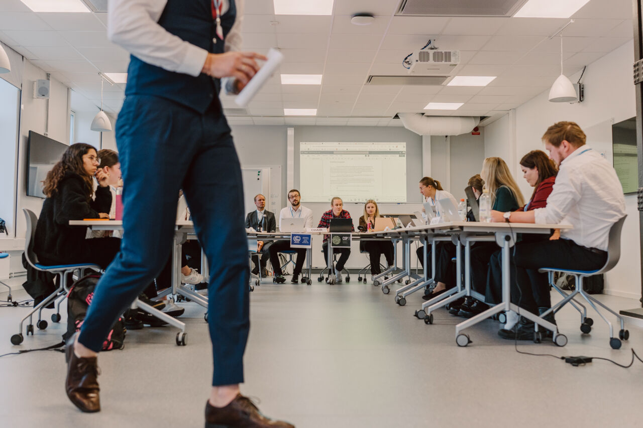 Studenter sitter vid bord i en halvcirkel i en seminariesal