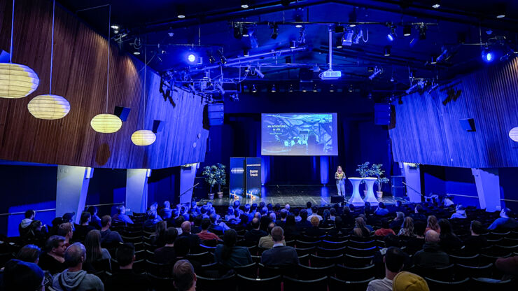 Photo of a person standing on a stage in front of an audience.