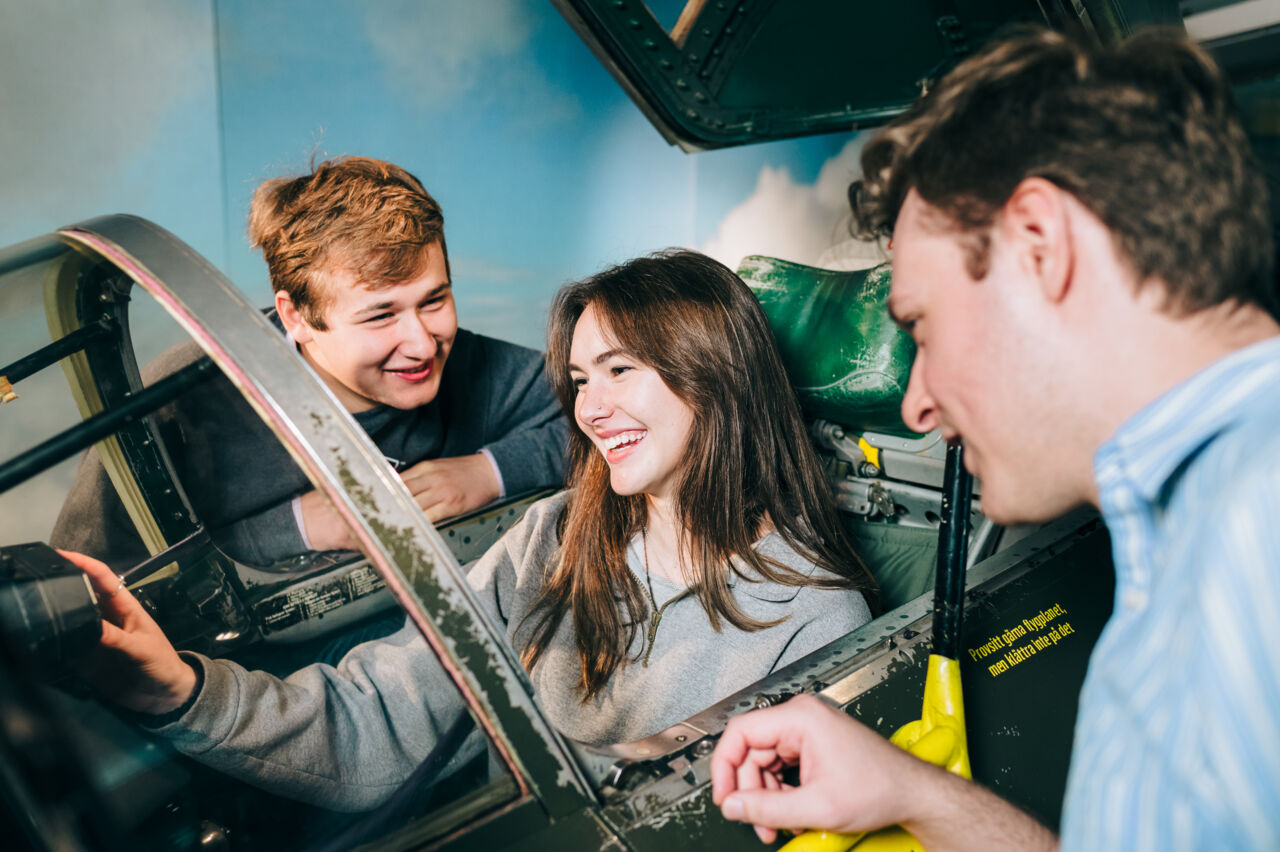 Tre personer sitter vid en simulator