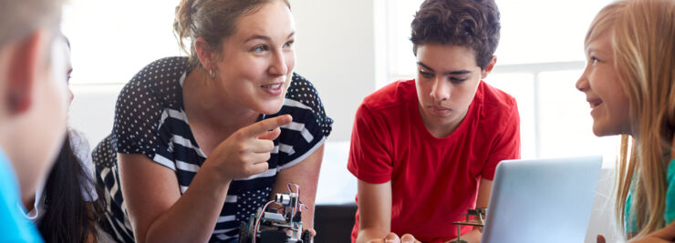 Happy teacher with students building a robot.