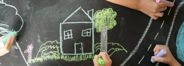 Children's hands paint a house with crayons.