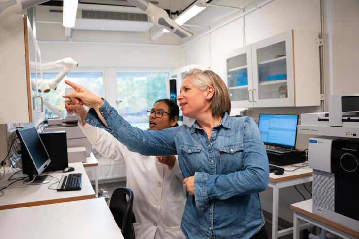 Två kvinnor i laboratoriet. De pekar på något utanför bild.